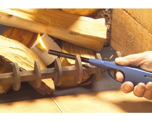 Person zündet Brennholz mit einem Stabfeuerzeug an