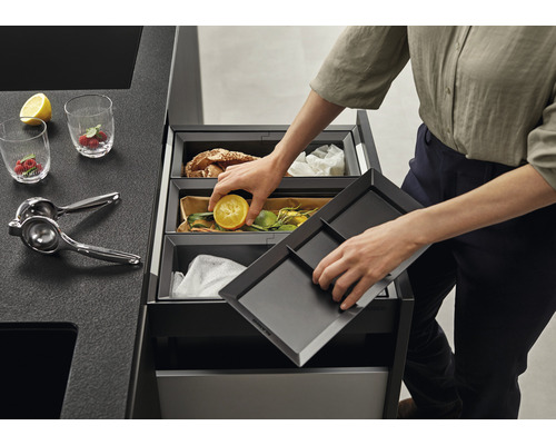 Mülltrennsystem mit Person beim Einwerfen einer halben Zitrone.