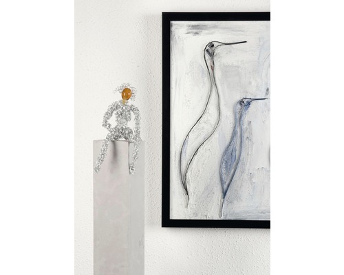Dekorative Szene mit einer Drahtfigur auf einem Sockel und einem gerahmten Gemälde an der Wand.