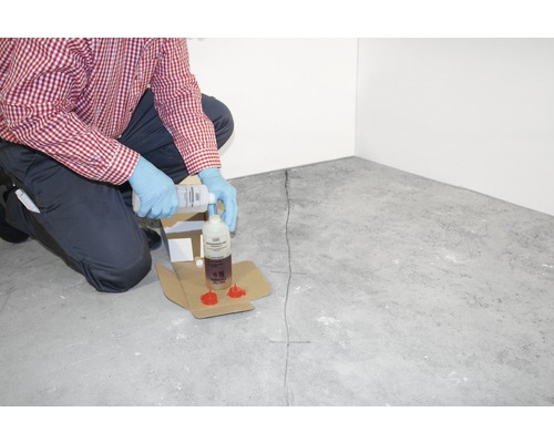 Anwender gießt Rissinjektionsmittel in eine Flasche für die Rissreparatur