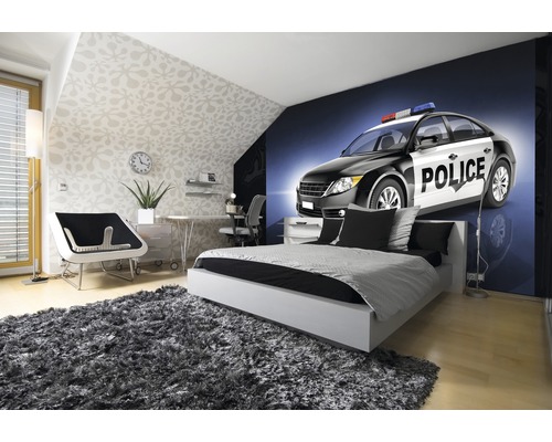 Helles Schlafzimmer mit Bett, Schreibtisch und Fototapete eines Polizeiautos
