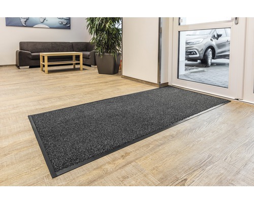 Graue Schmutzfangmatte vor einer Tür in einem Flur.