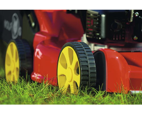 Detailaufnahme eines Rasenmähers mit gelben Rädern im Gras