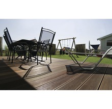 Terrasse mit Terrassendielen, Gartentisch, Stühlen und Spielplatz im Garten.