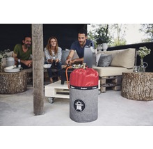 Szene mit einer Gasflasche mit Abdeckung und drei Personen beim Grillen im Freien