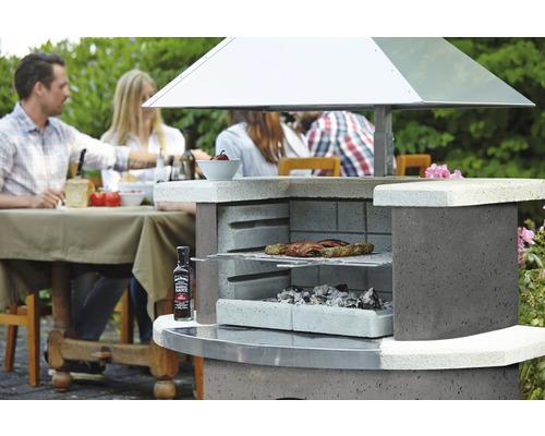 Gemauerter Grill mit Grillgut und sitzenden Personen