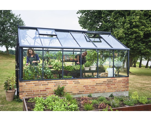 Gewächshaus mit Pflanzen und zwei Personen im Garten.