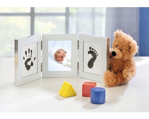 Dreiteiliger Bilderrahmen mit Babyfoto, Handabdruck und Fußabdruck neben Teddybär und Bauklötzen