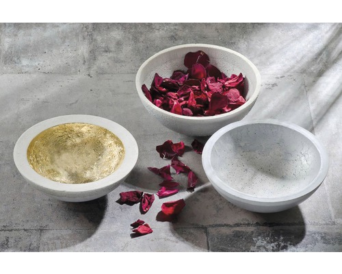 Drei Betonschalen, eine mit Gold ausgelegt, eine mit Rosenblättern gefüllt, eine leer.