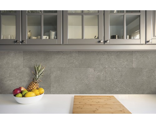 Küchenszene mit grauen Wandfliesen, Obstschale und Schneidebrett