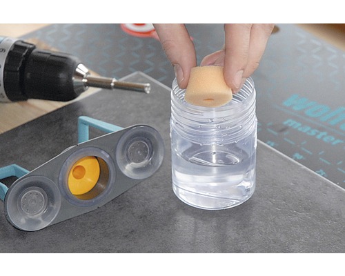 Fliesenwerkzeug im Einsatz mit Schwamm, Behälter mit Reinigungsflüssigkeit und Bohrmaschine