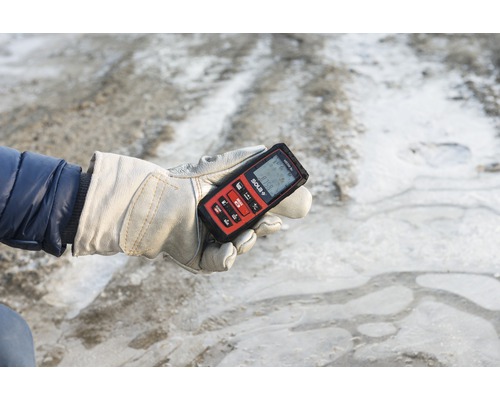 Person mit Arbeitshandschuh hält Solat Laser-Entfernungsmesser in der Hand