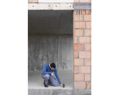 Handwerker misst mit einem Laser-Entfernungsmesser in einem Rohbau