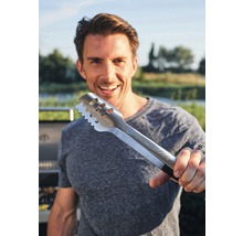 Eine Person hält eine Grillzange aus Metall in der Hand.