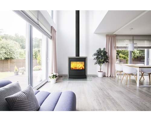 Wohnzimmer mit Kaminofen, Sofa, Esstisch und großen Fenstern