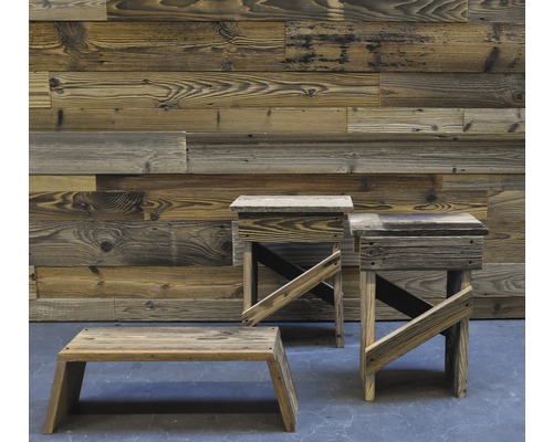 Drei Holzhocker vor einer Holzwand.