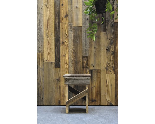 Holzhocker vor einer Wand aus Altholzpaneelen mit einer Hängepflanze