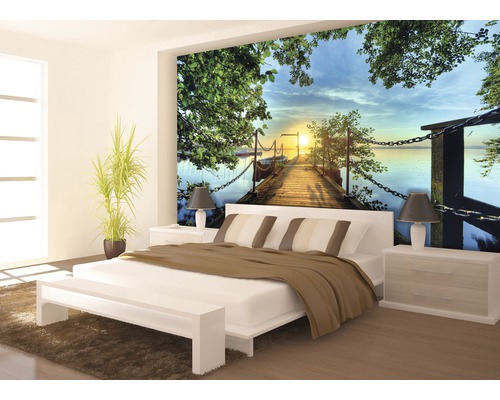 Schlafzimmer mit Fototapete eines Holzstegs bei Sonnenuntergang über einem See