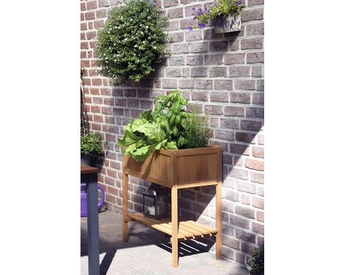 Hochbeet aus Holz mit Pflanzen und Ablagefläche vor einer Ziegelwand