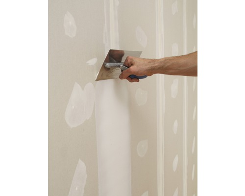 Eine Person spachtelt eine Trockenbauwand mit einer Spachtel