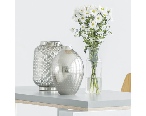 Dekorative Szene mit Windlicht, Vase und Blumenstrauß auf einem Tisch.