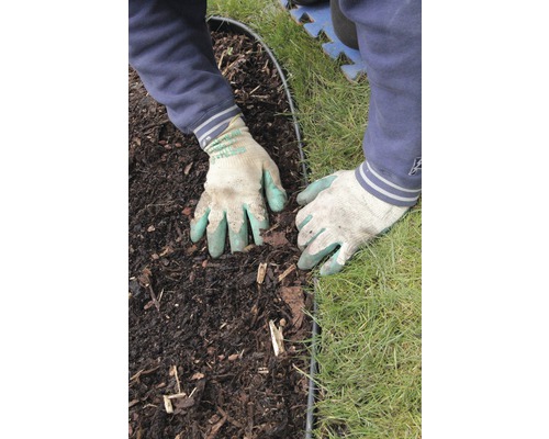 Hände mit Gartenhandschuhen arbeiten an einer Beeteinfassung zwischen Erde und Rasen.