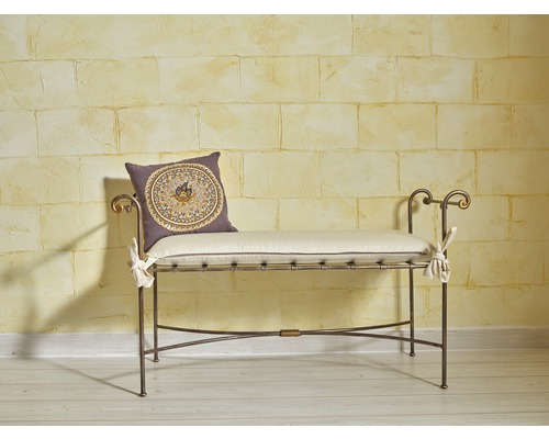 Dekoratives Sitzmöbel mit Kissen vor einer Wand