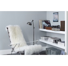 Wohnzimmer mit Sessel, Lammfell, Stehlampe und Regal an der Wand