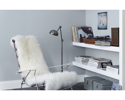 Wohnzimmer mit Sessel, Lammfell, Stehlampe und Regal an der Wand