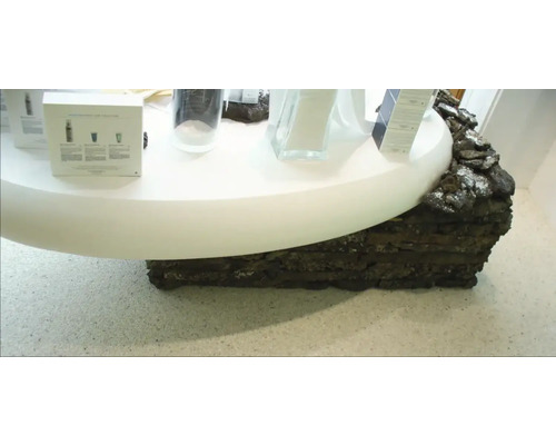 Präsentationstisch mit Hautpflegeprodukten und Dekor aus Lavastein