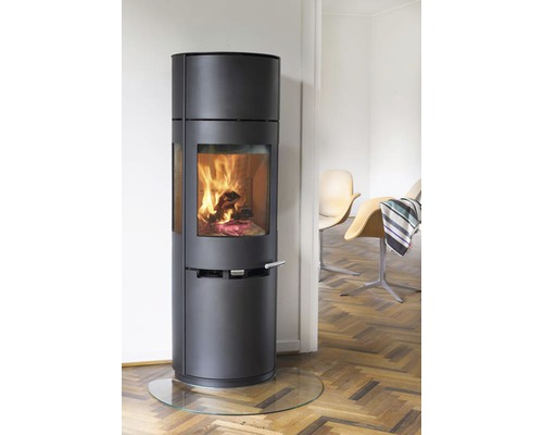 Kaminofen mit Glasbodenplatte in einem Wohnraum mit Holzboden und Stühlen.