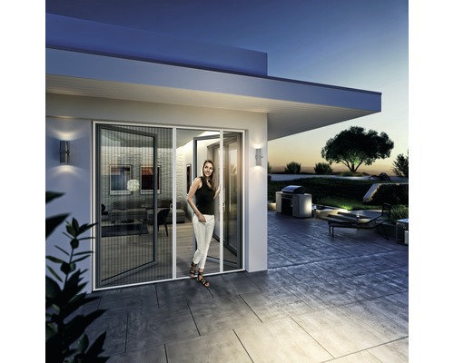 Frau steht in geöffneter Insektenschutztür auf einer Terrasse