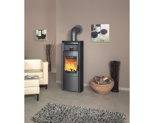 Wohnzimmer mit Kaminofen, Sessel, Korb mit Holz und Teppich