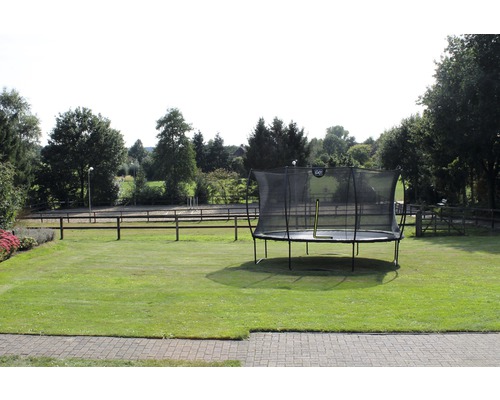 Aufblasbares Gartentrampolin mit Sicherheitsnetz auf einer Rasenfläche.