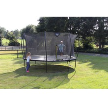 Trampolin mit Sicherheitsnetz und spielenden Kindern im Garten