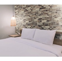 Schlafzimmer mit Doppelbett, Nachttisch und Wand in Backsteinoptik