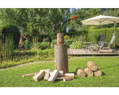 Axt im Holzblock mit Holzscheiten im Garten.