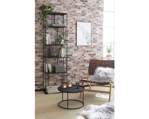 Wohnzimmer mit Regal, Tisch und Sessel vor einer Ziegelwand