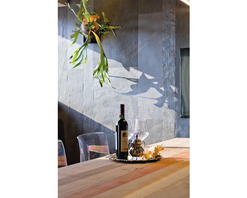 Dekoratives Arrangement mit Weinflasche, Glas, Kanne und Pflanzen auf einem Esstisch