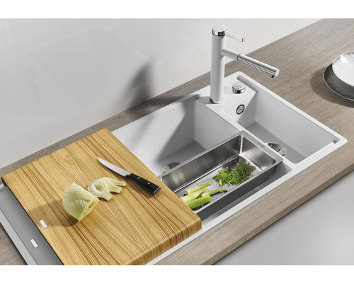 Küchenspüle mit Armatur, Schneidebrett, Gemüseschale und geschnittenem Gemüse.