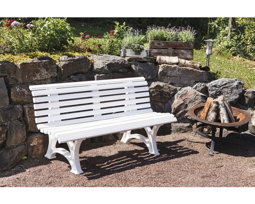 Weiße Gartenbank aus Holz vor einer Steinmauer