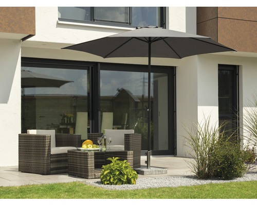 Sitzgruppe mit Sonnenschirm auf einer Terrasse vor einem Haus