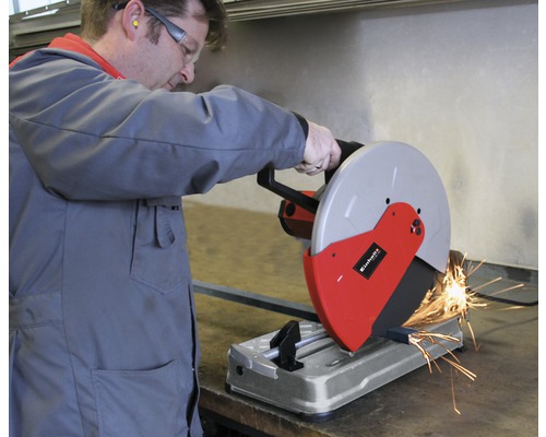Ein Mann bedient eine Metallsäge beim Schneiden eines Metallstücks. Funken fliegen.