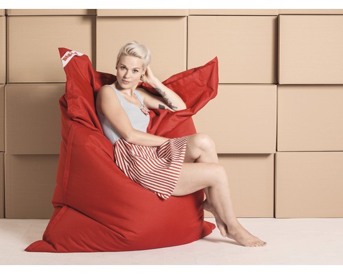Frau sitzt entspannt in einem roten Sitzsack vor Kartons.