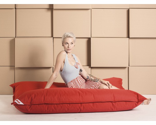 Frau sitzt auf rotem Sitzsack vor Umzugskartons