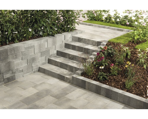 Außenaufnahme mit Pflastersteinen, Treppenstufen und Stützmauer im Garten.