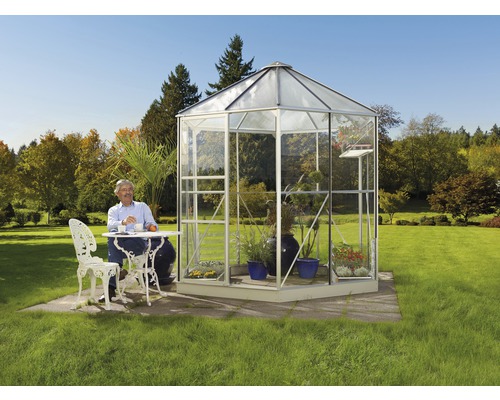 Freistehendes Gewächshaus aus Glas mit Mann an einem Tisch
