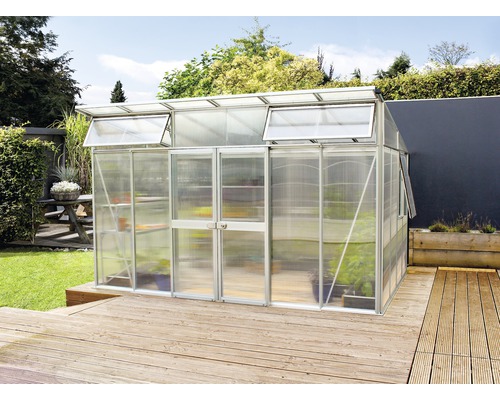 Gewächshaus Vitavia Aphrodite 11500 Hohlkammerplatten 10 mm 275x396 cm Aluminium Gewächshaus mit Regalen auf einer Holzterrasse in einem Garten.