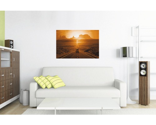 Wohnzimmer mit Sofa und Wandbild einer Straße in der Wüste bei Sonnenuntergang