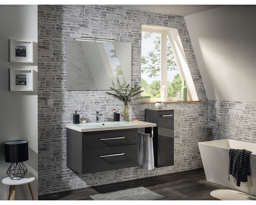 Modernes Badezimmer mit Waschtisch, Spiegel, Beleuchtung und Badewanne vor einer Steinwand